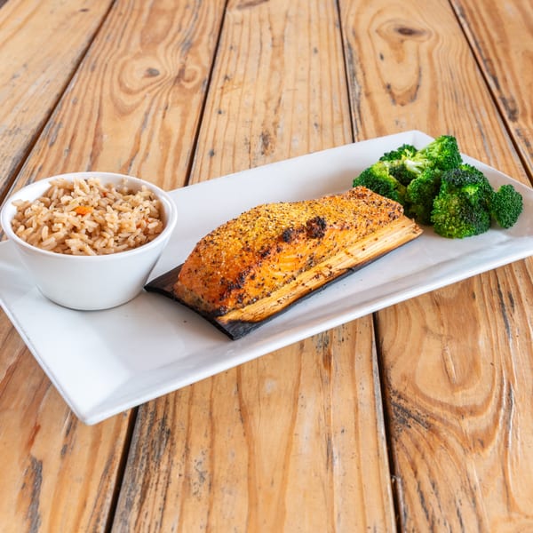 Cedar plank salmon with a side of brown rice and steamed broccoli on a white rectangular plate.